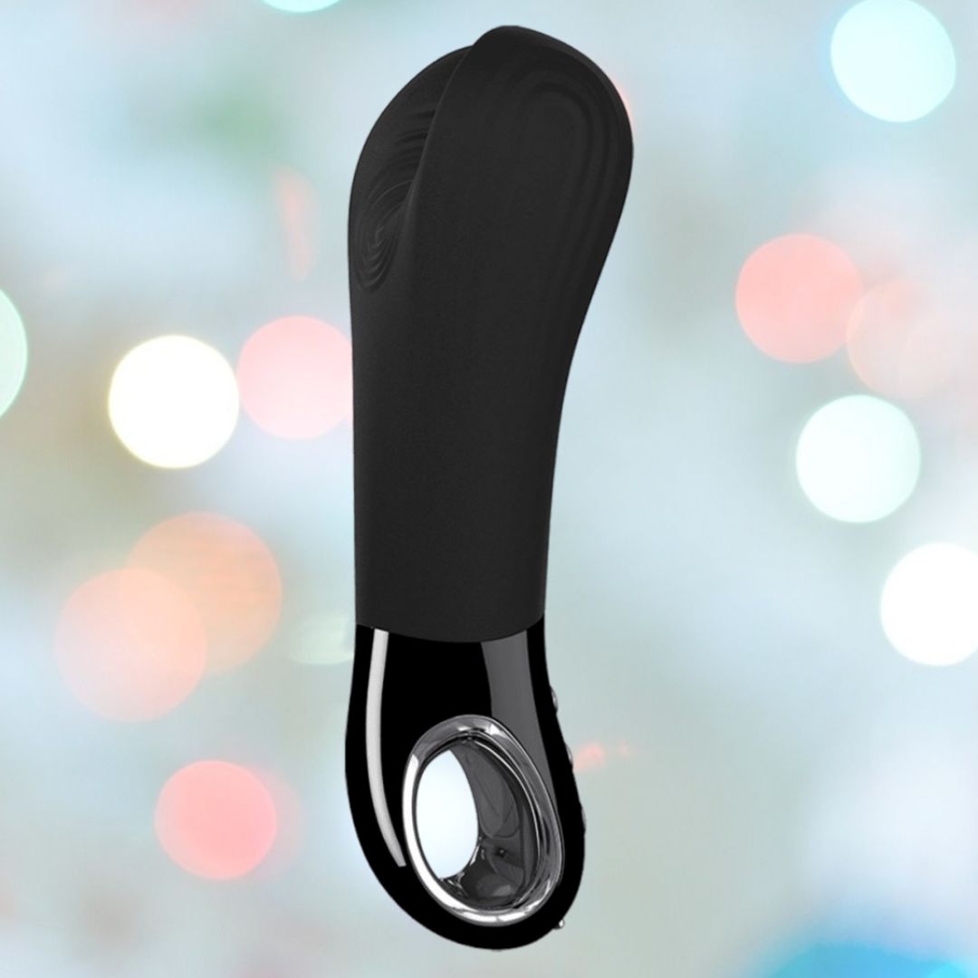 The Fun Factory Manta Rechargeable Vibrating Male Stroker for Men - Black is a sleek, black handheld device with a shiny metallic accent at the bottom, perfect for solo play. It is set against a blurred background featuring colorful bokeh lights.