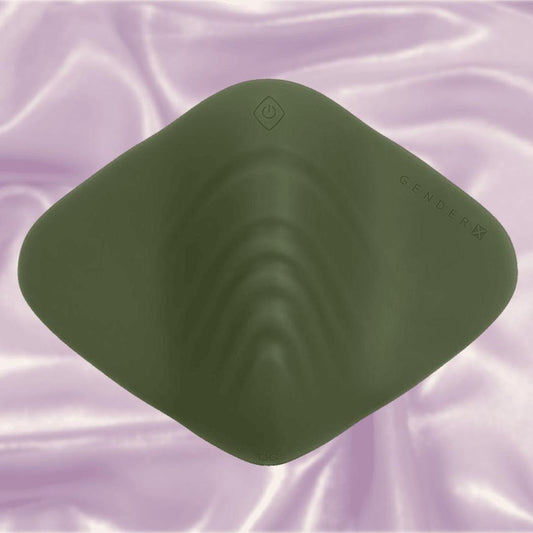 The Gender X Pleasure Pad by Evolved Novelties is a dark green, diamond-shaped silicone pad shown on soft pink satin for a gender-inclusive vibe. 1080