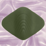 The Gender X Pleasure Pad by Evolved Novelties is a dark green, diamond-shaped silicone pad shown on soft pink satin for a gender-inclusive vibe.