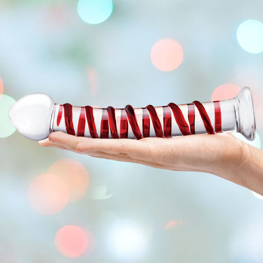 A hand holds a 10" Gläs Mr. Swirly Spiral Glass Dildo, elegantly wrapped with a red ribbon. The background is blurred with colorful bokeh lights, adding a touch of magic to the scene. 1080