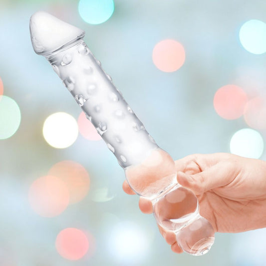 A person's hand is holding the Gläs 12" Double Ended Glass Dildo with Anal Beads, which has a cylindrical shape with a rounded end, suggesting temperature play. The background features a blurred array of soft bokeh lights in shades of white, green, and red. 1080