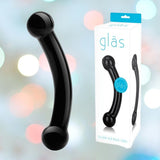 A black glass dildo is elegantly presented with its packaging, labeled "Gläs 5.5\" Double Bull Black Glass Dildo." Enhanced by a backdrop of colorful bokeh lights, this hypoallergenic piece from Gläs promises both allure and safety.