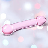 The Gläs Double Trouble Luxury Dual-Head Glass Dildo by Gläs, in purple, features rounded bulbs on both ends and is showcased against a soft pastel bokeh background.