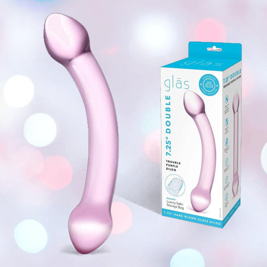 A curved, translucent light purple glass dildo by Gläs is shown beside its box, which features the name "Gläs Double Trouble Luxury Dual-Head Glass Dildo - Purple" and a photo of the product on a soft pastel background. 1080