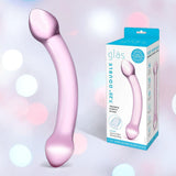 A curved, translucent light purple glass dildo by Gläs is shown beside its box, which features the name "Gläs Double Trouble Luxury Dual-Head Glass Dildo - Purple" and a photo of the product on a soft pastel background.