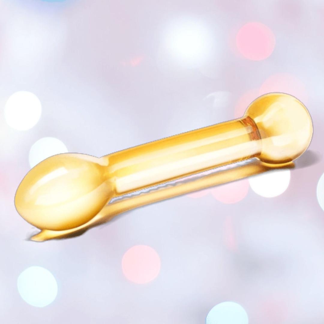The Gläs Honey Dripper 7" Double Ended Glass Anal and G-Spot Dildo by Gläs, in yellow with rounded ends, rests on a soft background with white, pink, and blue bokeh lights—ideal for P-Spot or G-Spot pleasure.