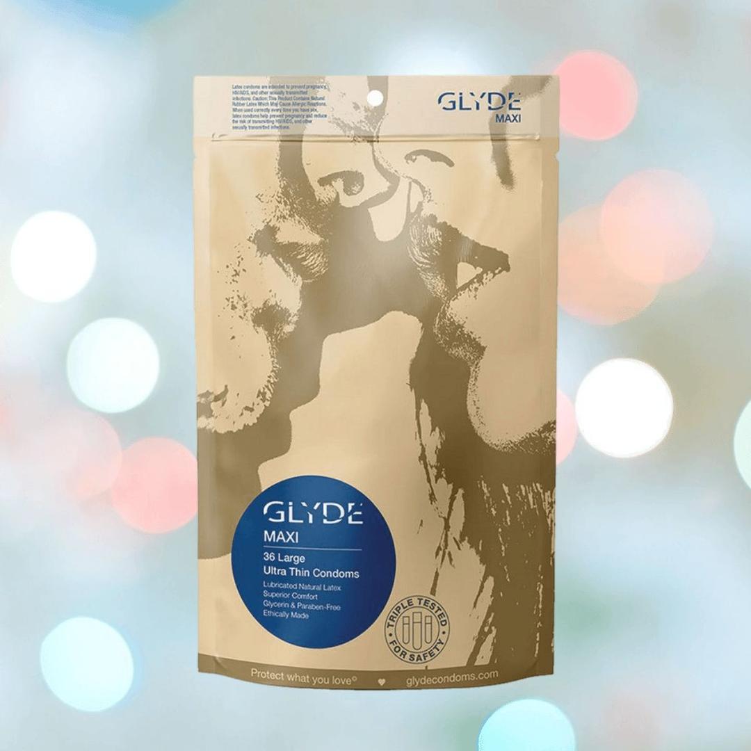 A package of Glyde Maxi LARGE Size Vegan Condoms by Glyde, featuring an abstract image of two people kissing. The bag contains 36 ultra-thin, natural rubber latex condoms set against a blurred, colorful background.