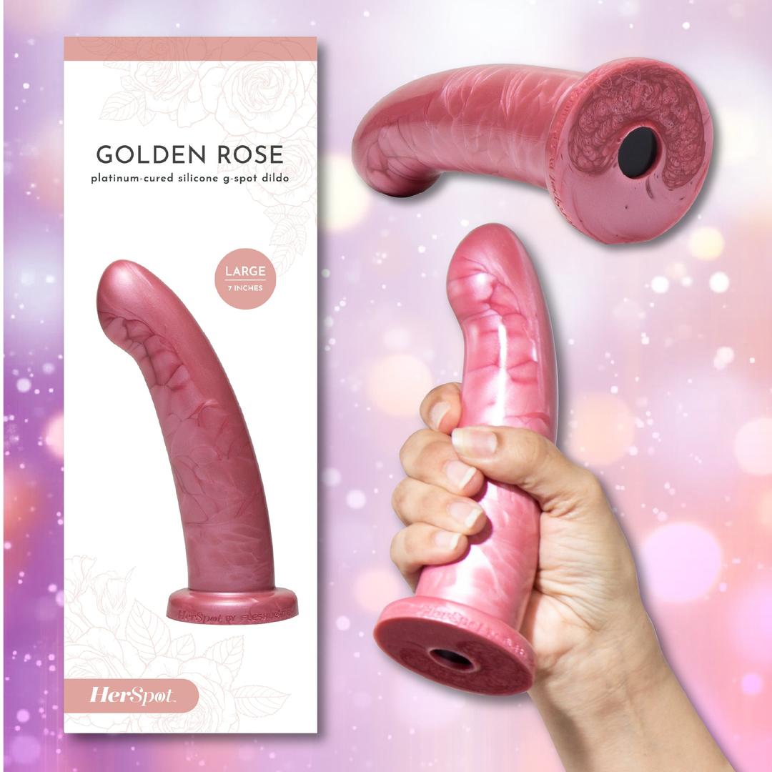 A hand holds the Fleshlight HerSpot Golden Rose Dildo by Fleshlight—a pink, curved platinum-cured silicone toy—in front of packaging labeled "Golden Rose" and "Large 7 inches," set against a pastel floral background.