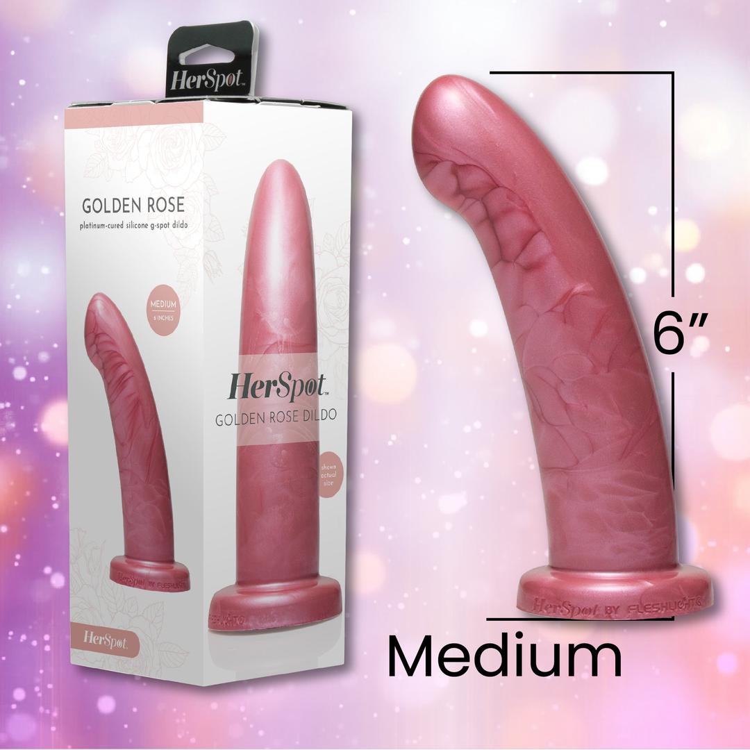 A Fleshlight HerSpot Golden Rose Dildo made of platinum-cured silicone stands upright by its packaging, showing the 6-inch medium size and Fleshlight branding. A soft, blurred pink background adds an elegant touch.
