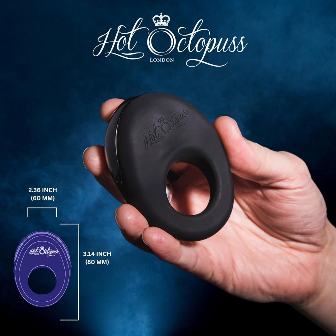 A hand holds the Hot Octopuss Atom - Vibrating Cock Ring, recognized for its powerful vibrations, against a dark blue background. The "Hot Octopuss London" logo is displayed prominently. Text on the image specifies dimensions: 2.36 inches (60 mm) and 3.14 inches (80 mm).