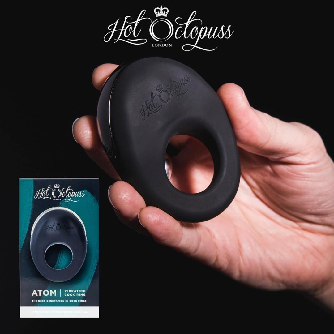 A hand is shown holding the Hot Octopuss Atom - Vibrating Cock Ring, promising an intense climax, with the brand logo prominently displayed above. Below, sleek packaging showcases the product image alongside the text "Hot Octopuss Atom - Vibrating Cock Ring." The dark background highlights this tool designed for delivering powerful vibrations.