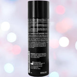 A black cylindrical bottle of ID Backslide Silicone Anal Lubricant by ID Lubricants, featuring a label with white text listing ingredients, directions, and manufacturing details, set against a softly blurred pink, blue, and white background.