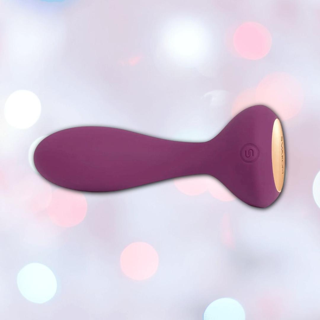 The Svakom JULIE Wearable Anal & G-Spot Vibrator features a rounded, ergonomic purple silicone design with a gold accent, displayed against a soft pastel bokeh background.
