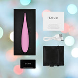 The LELO DOT Travel Clitoral Pinpoint Vibrator Pink, a teardrop-shaped electronic device from LELO, is elegantly housed in a black box featuring Infinite Loop Technology. It comes with a white USB cable, a black storage pouch, a warranty registration card, and a user manual—all beautifully set against colorful bokeh lights for an elegant touch.