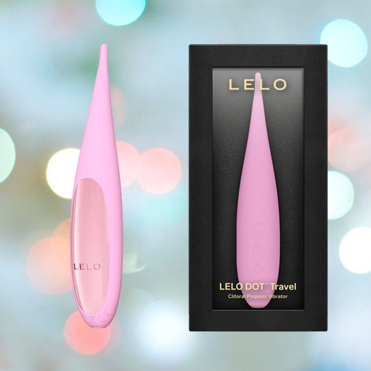 A LELO DOT Travel Clitoral Pinpoint Vibrator in pink, featuring the innovative Infinite Loop Technology, sits beside its sleek black and pink retail box labeled "LELO DOT Travel Clitoral Pinpoint Vibrator Pink," set against a dreamy backdrop of pastel bokeh lights. 1080