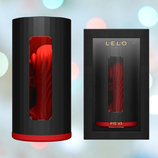 The image displays the LELO F1S V3 Male Masturbator Red, showcasing its advanced smart technology in its packaging. The cylindrical device features a striking black and red design, visible through a clear window on the sleek black box decorated with gold branding. The background highlights a light bokeh effect. 1080