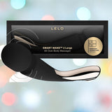 The LELO Smart Wand 2 Large - Luxury Wand Massager Black by LELO is displayed before its packaging, set against a blurred pastel background with soft circular lights—ideal for relaxation and sensual pleasure.