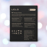 The image displays the black packaging box for the LELO F2S Massager & Stroker: Dual-Ended Masturbator with App Control - Red, featuring white product information and certification details against a pink, blue, and white bokeh background.