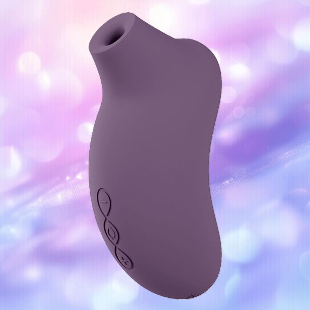 The LELO Sona 3 Cruise - Plum is a body-safe silicone massager with a curved design and three buttons, shown against a soft, blurred pink and purple background.