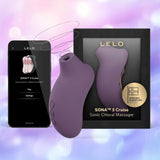 A LELO Sona 3 Cruise - Plum clitoral massager is pictured beside its box and a smartphone showing the app interface, set against a blurred pink and purple background.