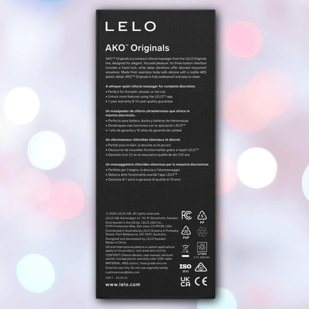 Purple LELO AKO™ Originals rectangular box with white text showing waterproof vibrator features in English and Spanish, legality icons, and company details, displayed on a softly blurred pastel pink and blue background.