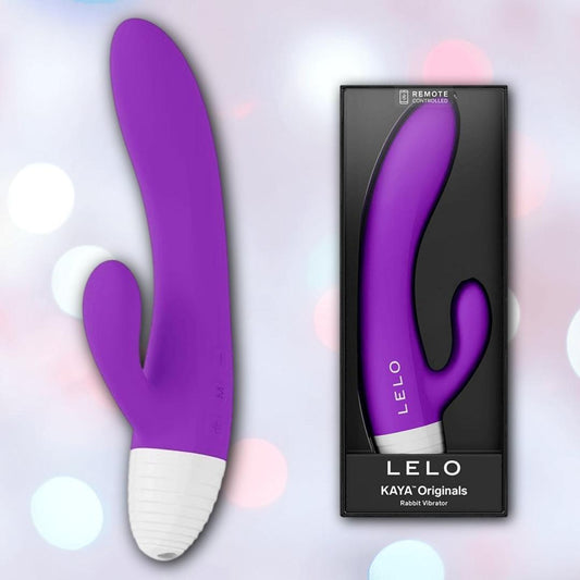 The LELO KAYA Originals Purple by LELO, a dual-action rabbit vibe with a white base, is displayed beside its black packaging that showcases the product. The background features a light tone with blurred circular lights. 1080