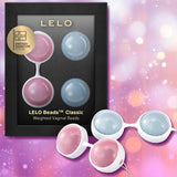A boxed set of Lelo LELO Luna Beads: Pelvic Floor Training Kegel Balls in pink and blue, shown in packaging and arranged outside against a purple bokeh background—ideal for enhancing pelvic floor wellness.