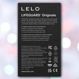 A black label for LELO’s Lelo LIFEGUARD Originals Purple showcases its waterproof, body-safe silicone design, warranty info, safety certifications, manufacturer details, and website—set against a blurred pastel backdrop with circular light spots.