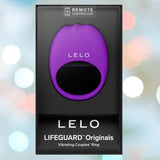 A boxed LELO LIFEGUARD Originals Purple vibrating couples’ ring with "REMOTE CONTROLLED" at the top, set against a blurred background of pastel lights.