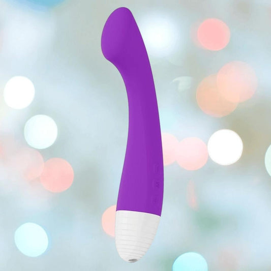 A purple LELO MOKA Originals G-spot vibe with a white base is displayed against a softly blurred background with pastel bokeh lights. 1080