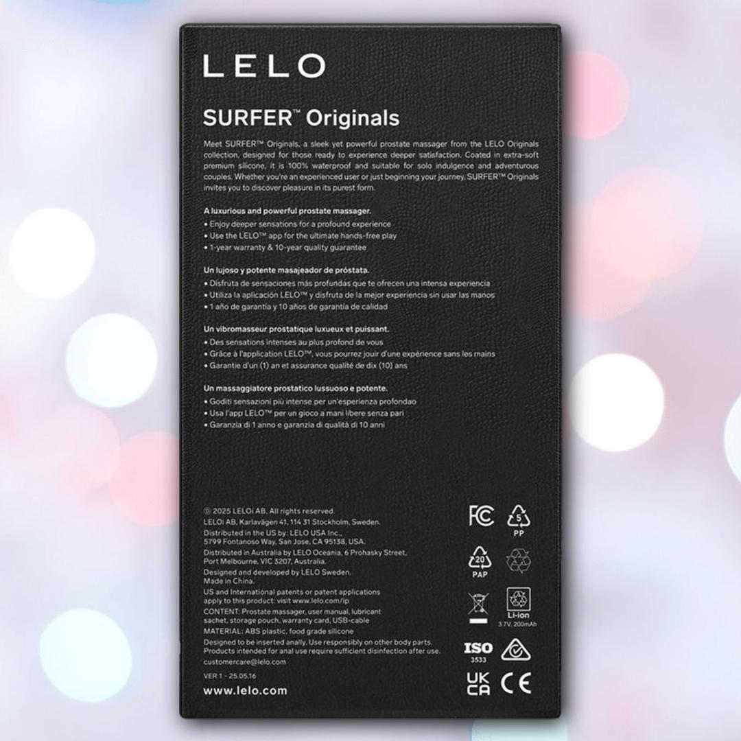 A black rectangular box for the LELO SURFER Originals Purple vibrating ring, showing white text in four languages. The rechargeable, waterproof box stands before a blurred background with pink, blue, and white light bokeh.
