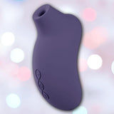 The LELO Sona 3 - Cyber Purple is a curved silicone suction vibrator with SenSonic technology and three side buttons, shown against a softly blurred background with white and pink bokeh lights.