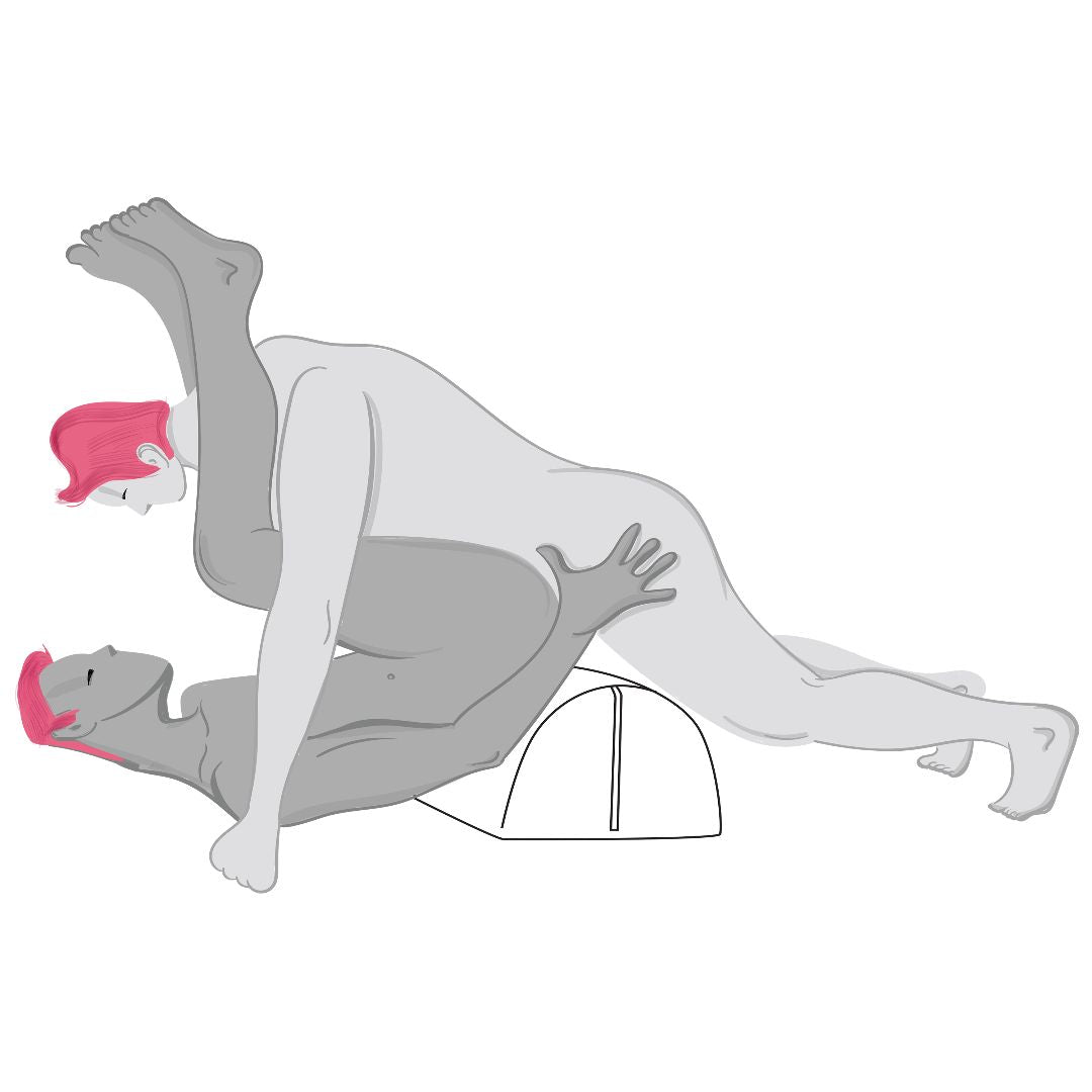 Two nude people with pink hair are having sex in a creative position. One reclines over a teal Liberator Bonbon Microvelvet cushion by Liberator, knees bent, while the other is on top facing them, lifting one leg high over their partner’s shoulder.