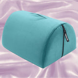 A teal Liberator Bonbon Microvelvet pillow by Liberator, dome-shaped with a zipper and handle, sits on shiny pale lavender satin—perfectly designed for hands-free solo play.
