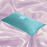 The Liberator Humphrey MicroVelvet - Teal by Liberator, a rectangular sex pillow with a flap and pocket, rests against a shiny light pink satin background.