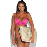 A smiling woman with long curly hair, wearing a pink bra and matching underwear, holds a beige zippered pouch—ideal for storing essentials like the Liberator Jaz Ibiza Collection - Natural sex position pillow by Liberator. Her left thigh shows a floral tattoo.