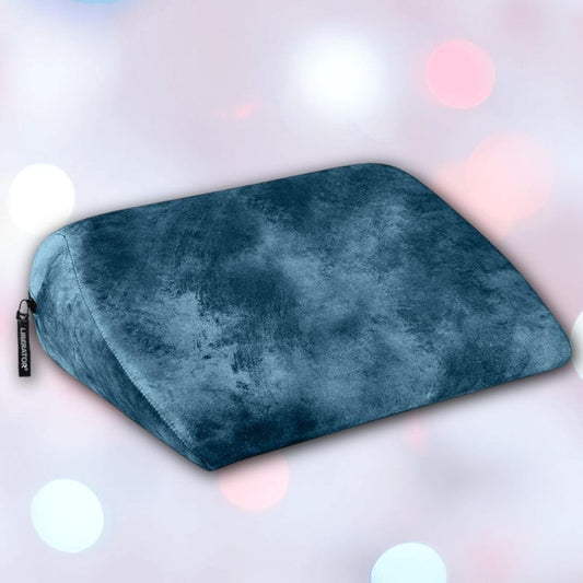 The Liberator Jaz Ibiza Collection - Ocean Blue by Liberator, a velvety wedge-shaped pillow with a small black tag, is displayed against a softly blurred background with pastel-hued circles. 1080