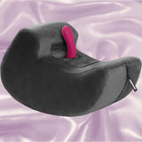 The Liberator Pulse MicroFiber - Black by Liberator is a black, curved, plush foam chair—ideal as sex furniture—with an upright handle on top, shown against a shiny lavender satin background.