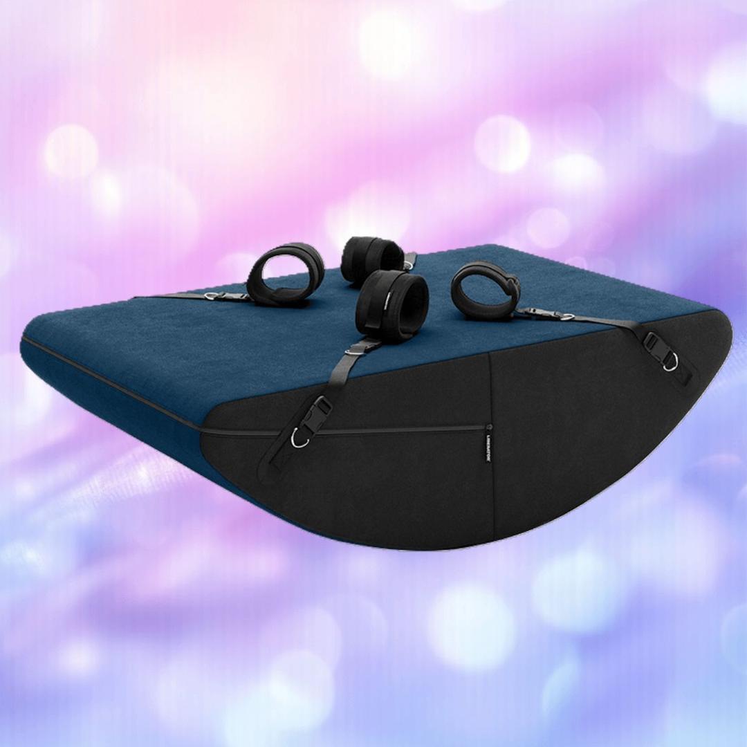 The Liberator Scoop Rocker: MicroLoop Bondage Edition with Cuffs by Liberator features adjustable black straps and buckles, set against a soft, blurred blue background.