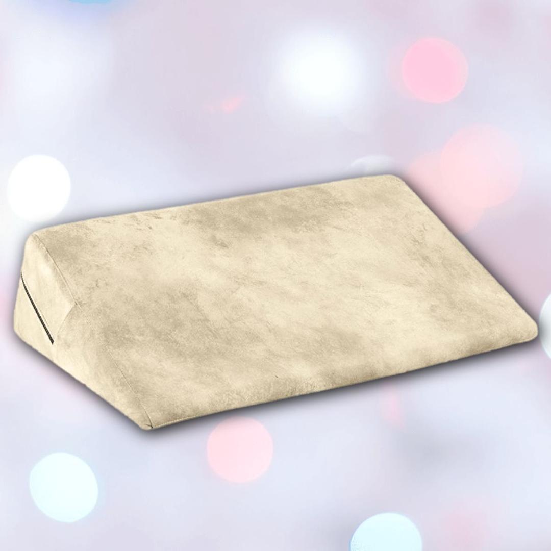 The Liberator Wedge Ibiza Collection - Natural by Liberator is shown in beige with a soft texture against a blurred pastel background featuring white, pink, and blue bokeh lights.