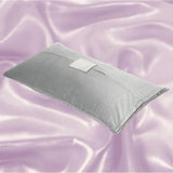 The Liberator Humphrey MicroVelvet - Grey by Liberator, a rectangular sex pillow with a small center flap and discreet toy pocket, is displayed on shiny pastel lavender satin fabric.