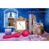 A magenta BMS Swan Sceptre Wand, a decorative crown, a purple candle, ornate books, and a golden-framed "swan" sign rest on a purple cloth. A blurred castle appears outside the window against the blue background.