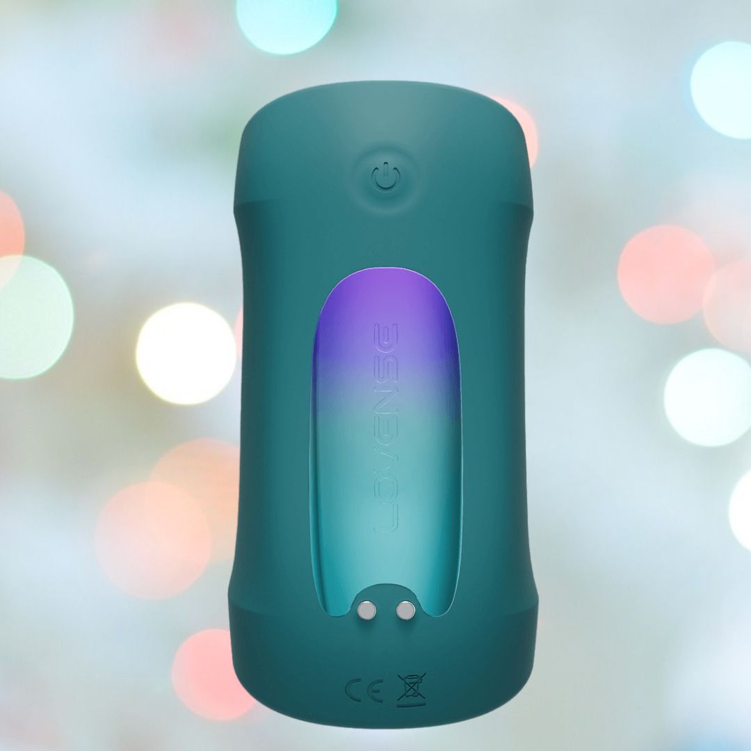 A teal Lovense device features a vertical, translucent section displaying the brand name against a blurred background of pastel bokeh lights in white, pink, and blue hues.