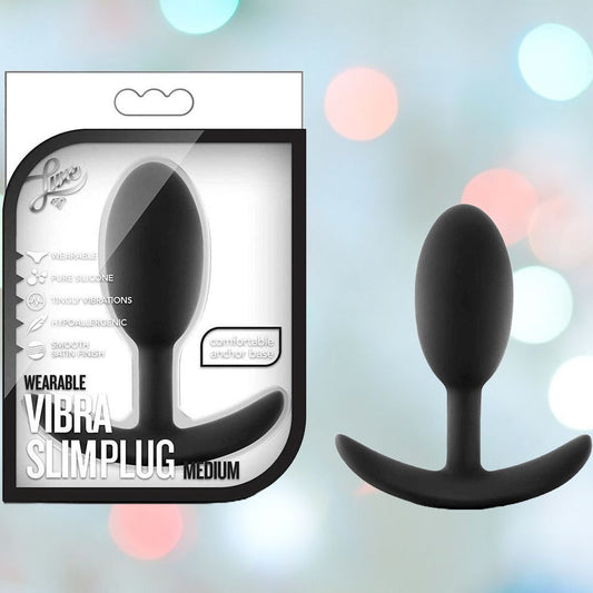 Packaging and product image of a Luxe Wearable Vibra Slim Black Butt Plug - Medium by Blush Novelties. The image highlights this wearable silicone anal plug, showcasing its "pure silicone" design, "intense vibrations," and a "comfortable anchor base." An elegant touch is added by the bokeh effect in the background, enhancing the appeal of this medium-sized plug. 1080