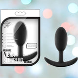 Packaging and product image of a Luxe Wearable Vibra Slim Black Butt Plug - Medium by Blush Novelties. The image highlights this wearable silicone anal plug, showcasing its "pure silicone" design, "intense vibrations," and a "comfortable anchor base." An elegant touch is added by the bokeh effect in the background, enhancing the appeal of this medium-sized plug.