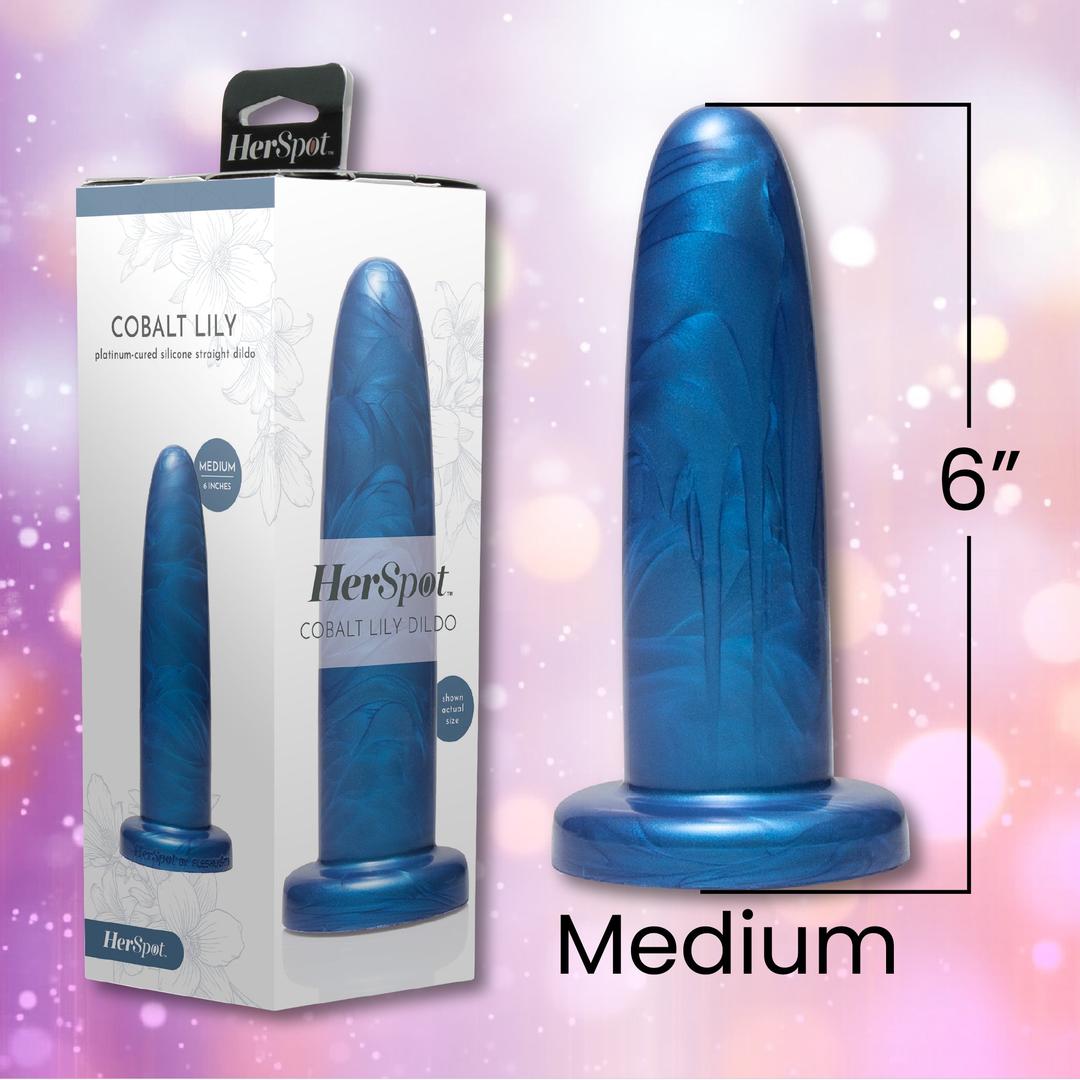 A blue Fleshlight HerSpot Cobalt Lily Dildo, 6 inches long with a marbled pattern and flared base, stands upright beside its packaging, offering medium-sized pleasure for those seeking new sensations.