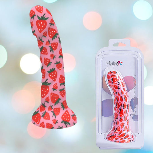 A Maia Juci Strawberry Themed Suction Dong 7" by Maia Toys, featuring a sturdy silicone design with a vibrant strawberry pattern and suction cup base, is pictured next to its packaging. The background is adorned with soft, multicolored bokeh lights. 1080