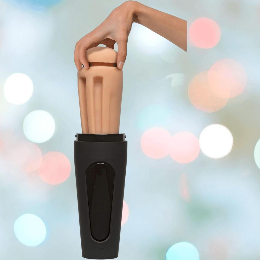 A hand holds the vanilla-colored Main Squeeze Endurance Trainer Stroker Pussy by Doc Johnson, placing it into a black container against a softly blurred pastel-lit background.