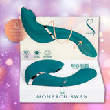 The BMS Swan The Monarch Swan - Teal, a luxurious dual-ended personal massager with suction and fluttering functions, is showcased in its open box against a sparkling purple-pink background.