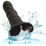 The CalExotics Monster Dong The Mummy, a realistic black liquid silicone dildo with a sturdy suction cup base, is shown in splashing water to highlight its waterproof design and wet environment suitability.